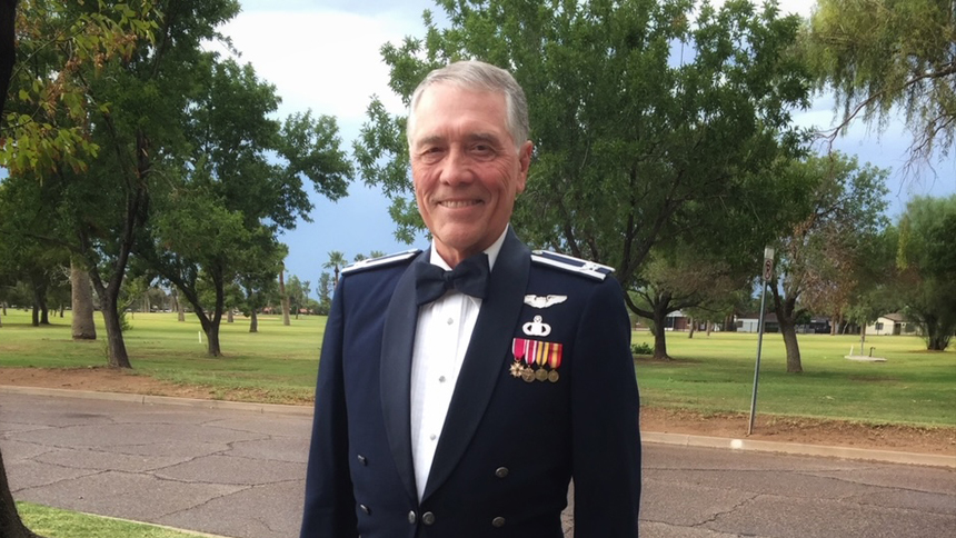 A photo of Roy Miller in military dress with a row of trees behind him.