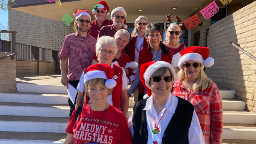 Smiling UUCP members and friends dressed for Christmas, gathered on the front steps