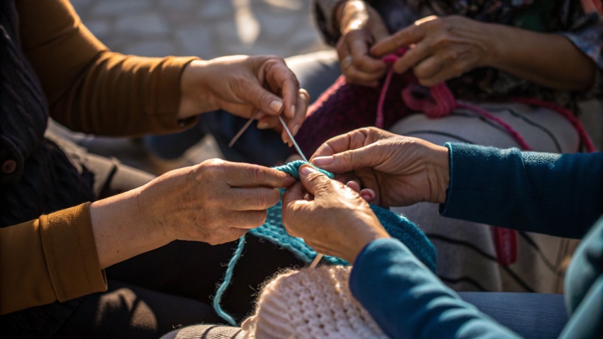 hands of people seating close to each other, crafting with yarn