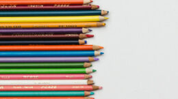 A group of colored pencils on a neutral grey background.